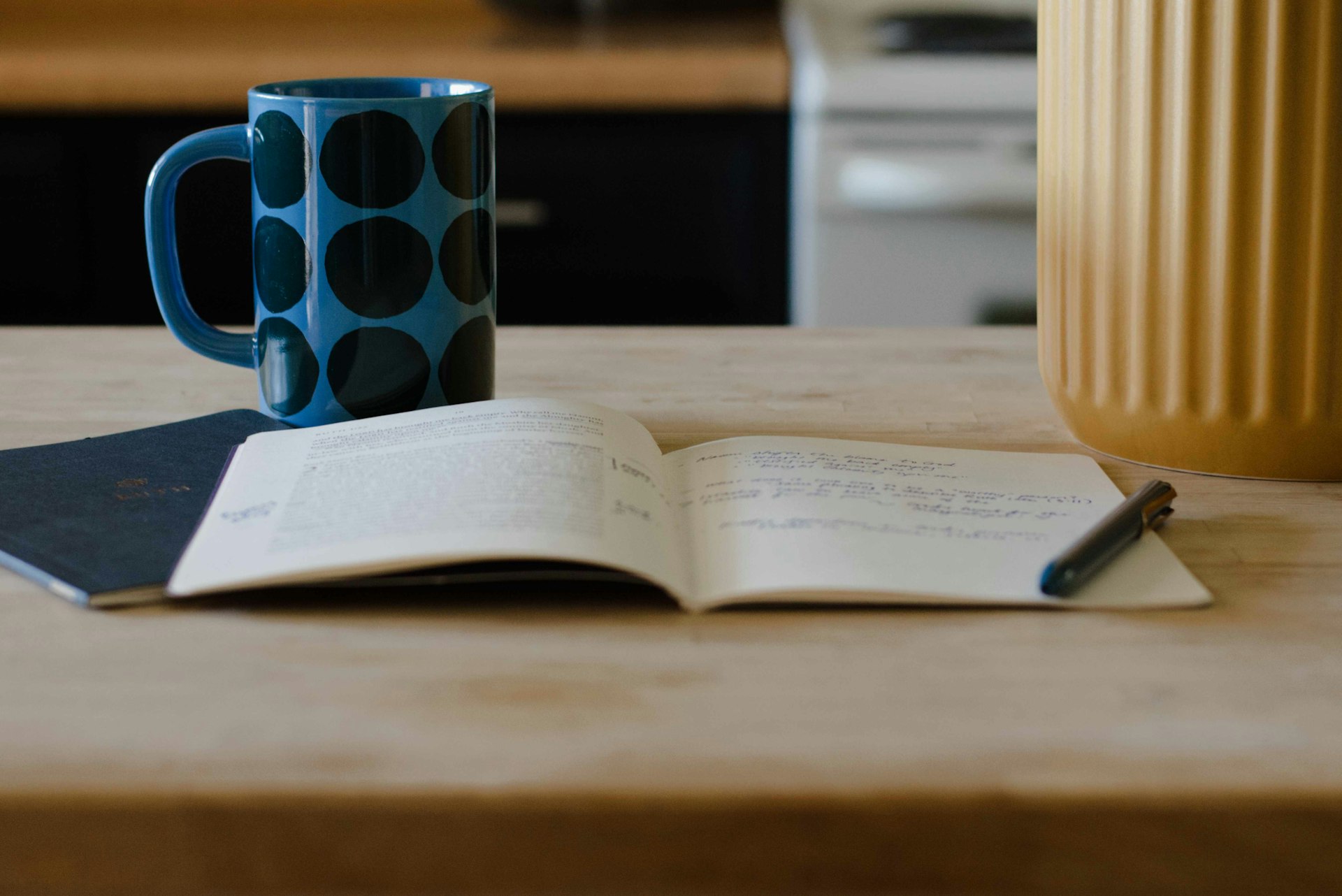 A mug, open notebook, and pen on a wooden table.